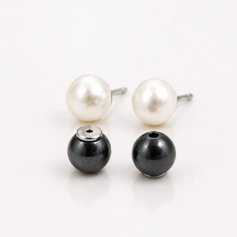 Pair of pearl earrings with a black bead on a white background