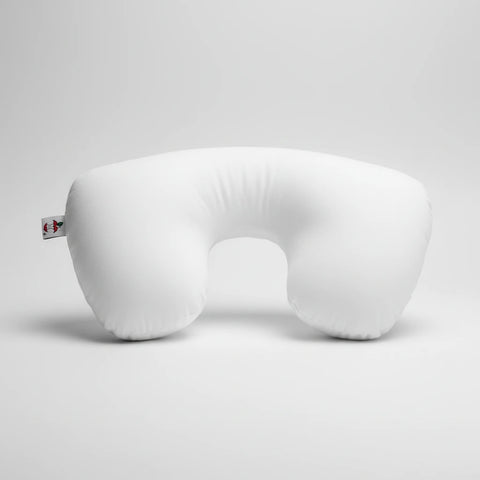 A white U-shaped travel neck pillow with a small red and green tag on the left side, shown against a plain white background.