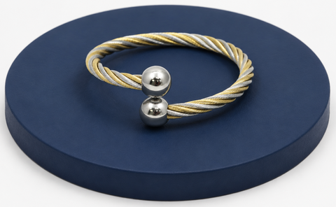 Bracelet with gold and silver cables on a dark blue circular stand