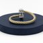 Two-toned bracelet on a dark blue stand with a white background