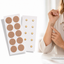Two sheets of Magnetic adhesive patches with gold dots, one sheet on a white background, and a person pointing to their arm with a patch on it.
