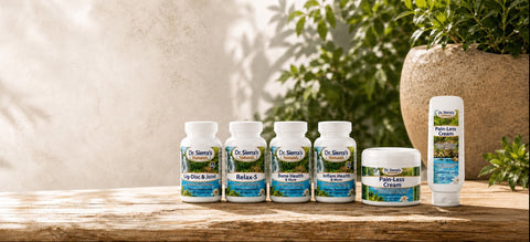 A set of Dr. Sierra's naturals products, including five supplement bottles, a jar, and a tube, arranged on a rustic wooden table with a warm, sunlit background and green plants.
