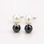 Pair of pearl earrings with a black bead on a white background