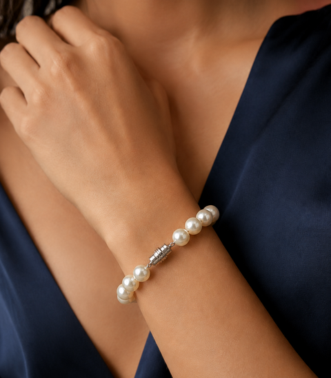 Pearl bracelet on a woman's wrist with a dark blue garment.