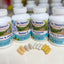 Four white bottles of Dr. Sierra's Naturals dietary supplements arranged in a row on a light surface, with five capsules placed in front.