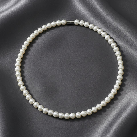 Pearl necklace with a silver-toned clasp, arranged in a circle on a dark gray satin fabric background.